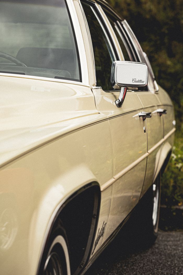 Close-up of a classic beige Cadillac car parked outdoors showcasing iconic design.